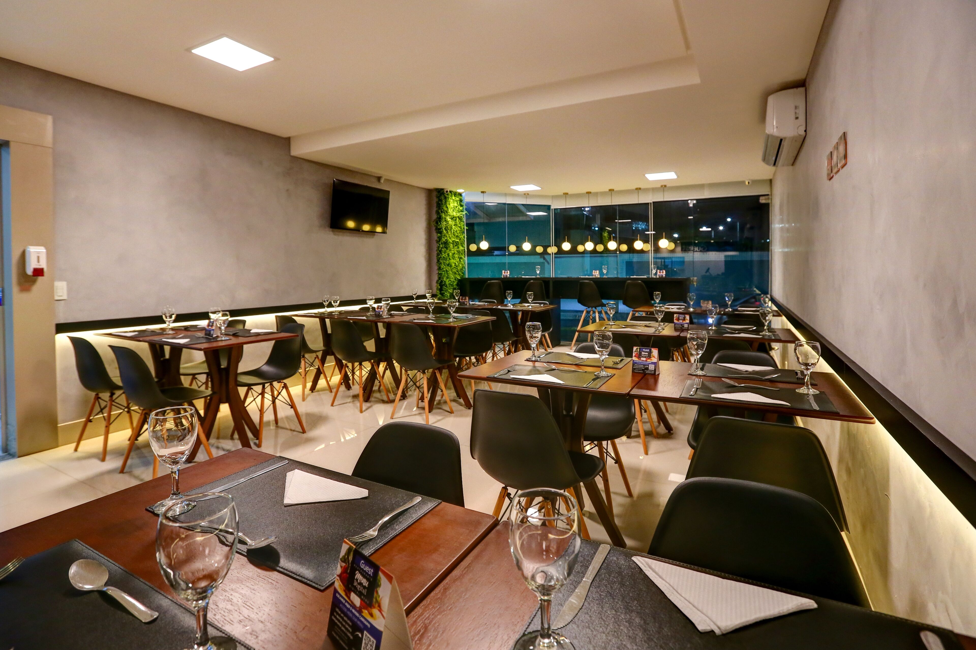 Een restaurant met meerdere tafels en stoelen, voorzien van wijnglazen en bestek.
