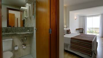 Habitación de hotel con baño, cama, ventana y balcón.