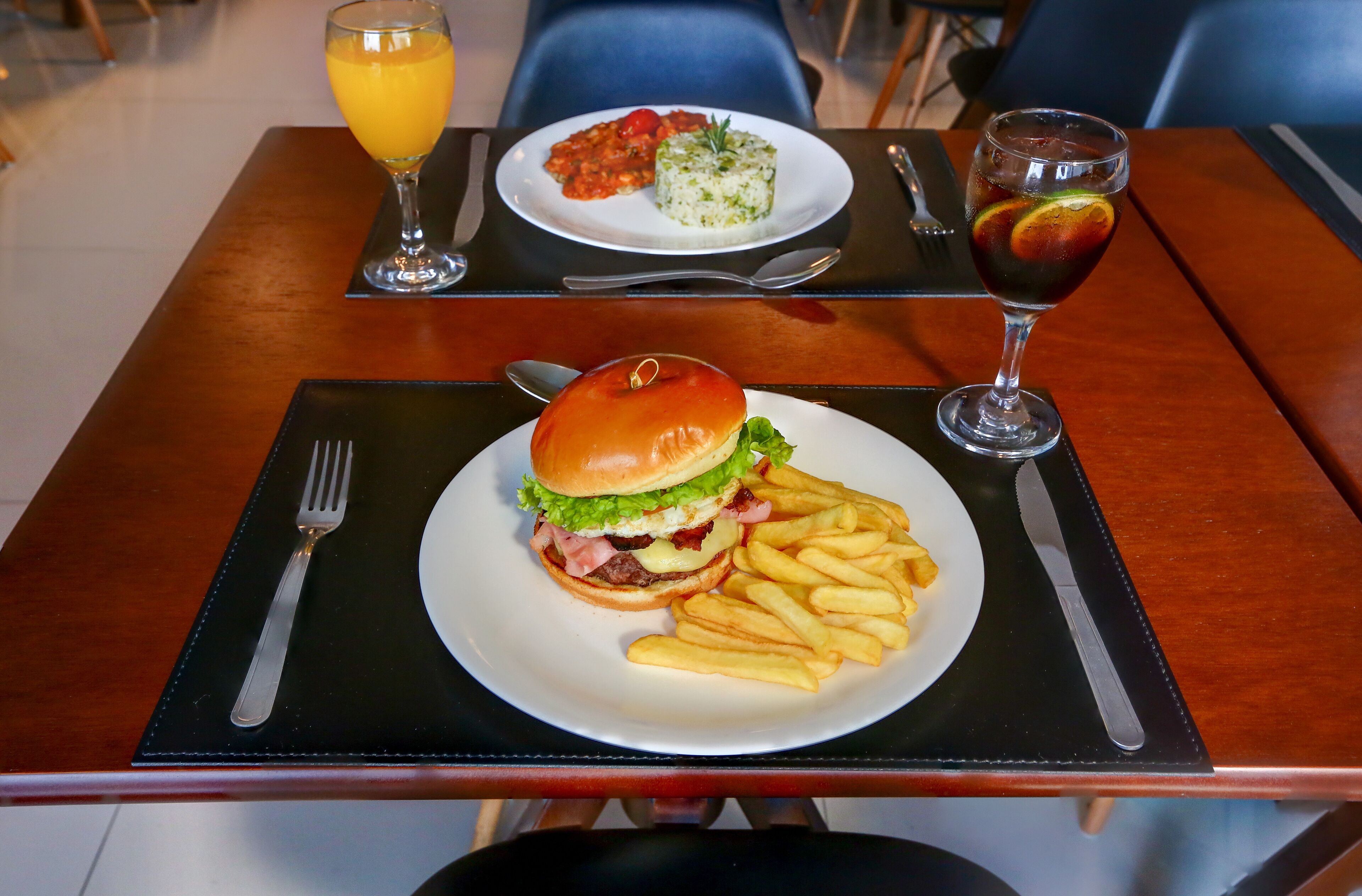 A meal consisting of a burger, fries, and a side salad on a wooden table.