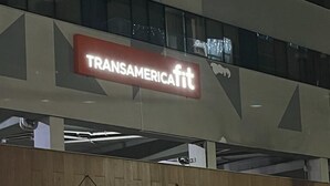 A Transamerica Fit building with a modern design, featuring a prominent sign, glass entrance, and a seating area outside.