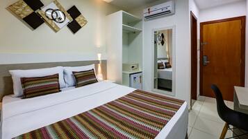 Una habitación de hotel con cama, escritorio, aire acondicionado y armario.