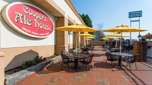 A patio area with tables and chairs, a sign for Cooper's Ale House, and a Wyndham Garden Hotel sign. - Wyndham Garden Greensboro (Greensboro)