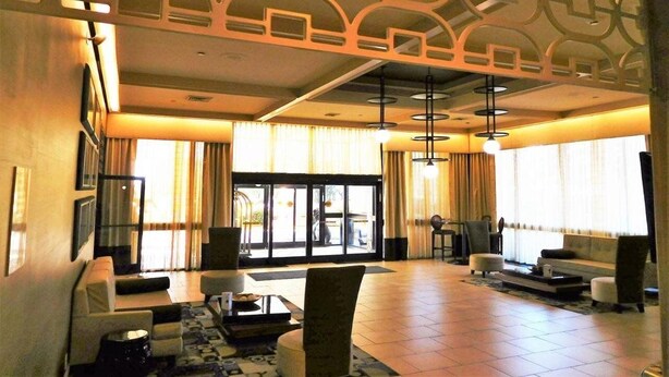 A spacious lobby with a modern design, featuring a seating area with sofas and armchairs, a coffee table, and a patterned rug. - Wyndham Garden Greensboro (Greensboro)