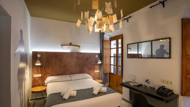 Habitación de hotel con cama, escritorio y una lámpara de papel original.