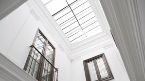 Una habitación con paredes blancas, un tragaluz y una ventana con marco de madera.