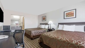 A hotel room with two beds, a desk, a chair, a lamp, and a painting on the wall. - Knights Inn Slaton (Slaton)