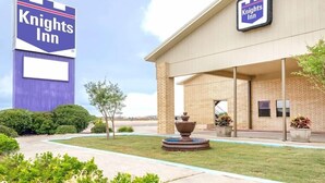A Knights Inn building with a large sign, a brick facade, and a fountain in the front. - Knights Inn Slaton (Slaton)