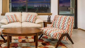 A living room with a sofa, armchair, coffee table, and patterned rug. - Knights Inn Slaton (Slaton)