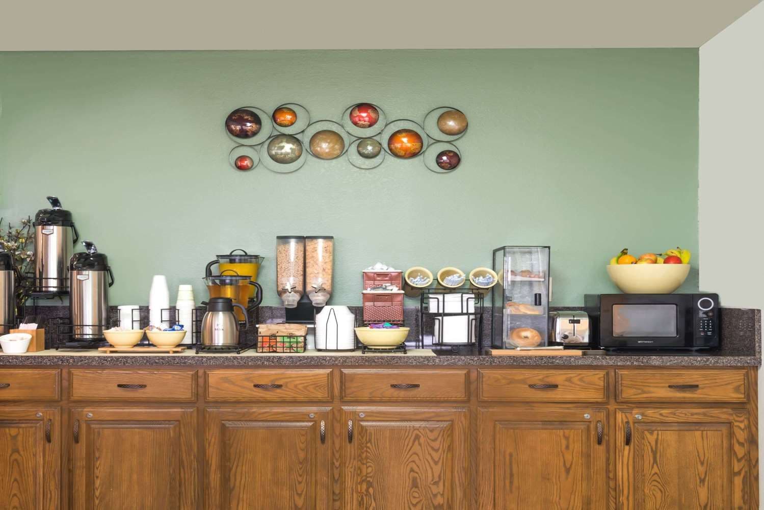 Cozinha com armários de madeira, espaço para café e uma fruteira no balcão.