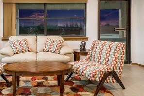 A living room with a sofa and armchair, a coffee table, and a patterned rug.