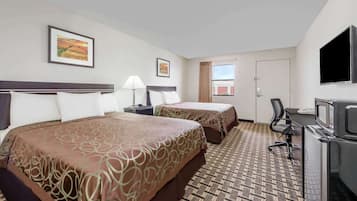 A hotel room with two beds, a desk with a TV, a window, and artwork on the walls.