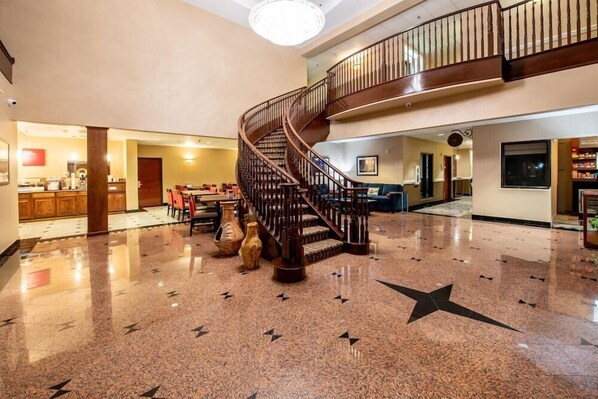 A spacious lobby with a polished marble floor, a grand staircase, and a seating area with chairs and tables. - Comfort Suites Houston Near Medical Center- NRG Stadium (Houston)
