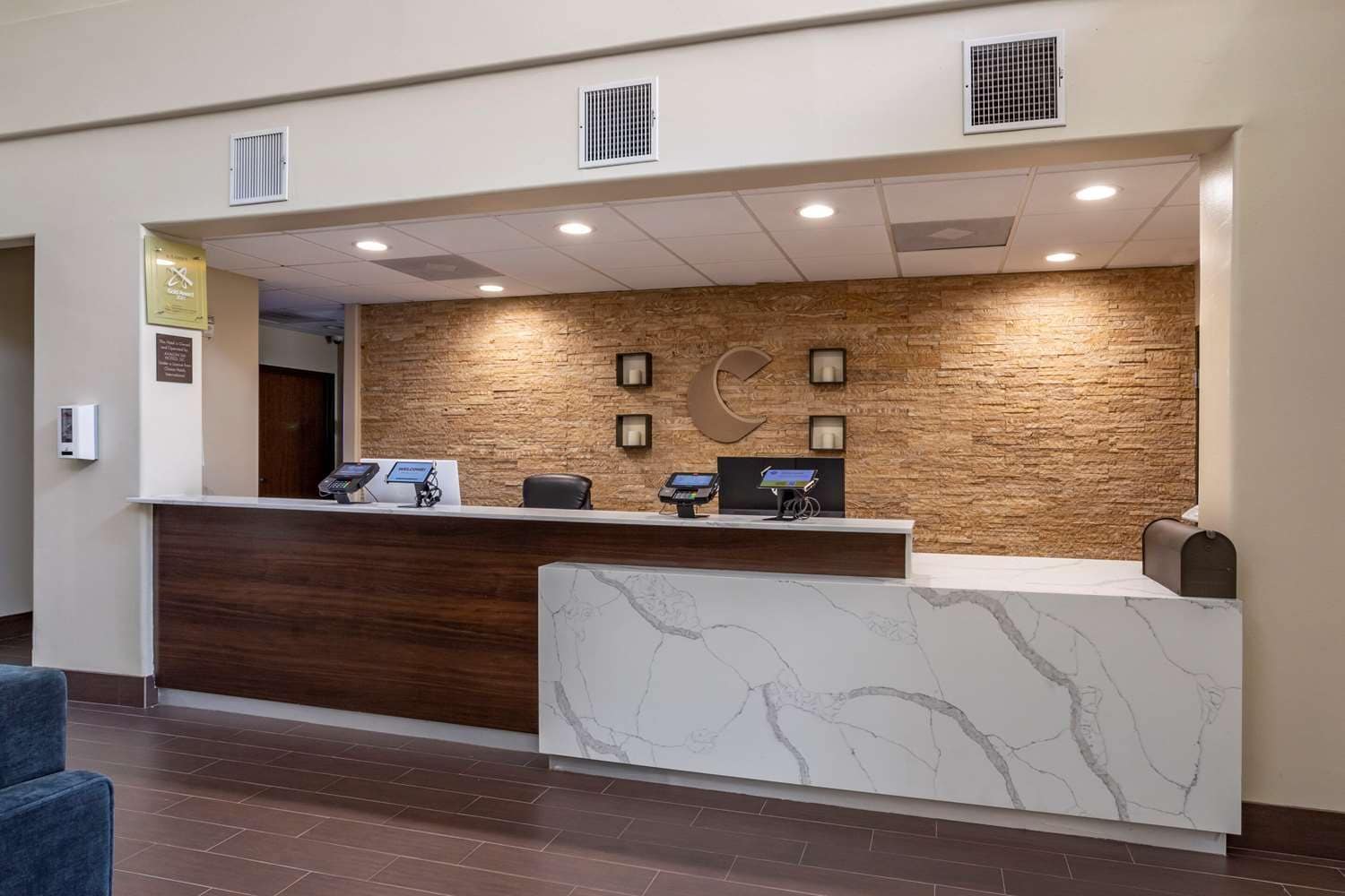 A reception desk with a marble counter, a wooden accent wall, and a stone wall backdrop.