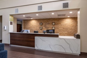 A reception desk with a marble counter, a wooden accent wall, and a stone wall backdrop. - Comfort Suites Houston Near Medical Center- NRG Stadium (Houston)