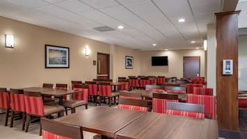 Uma área de refeições de hotel com várias mesas e cabines, equipada com televisões embutidas e iluminação ambiente.