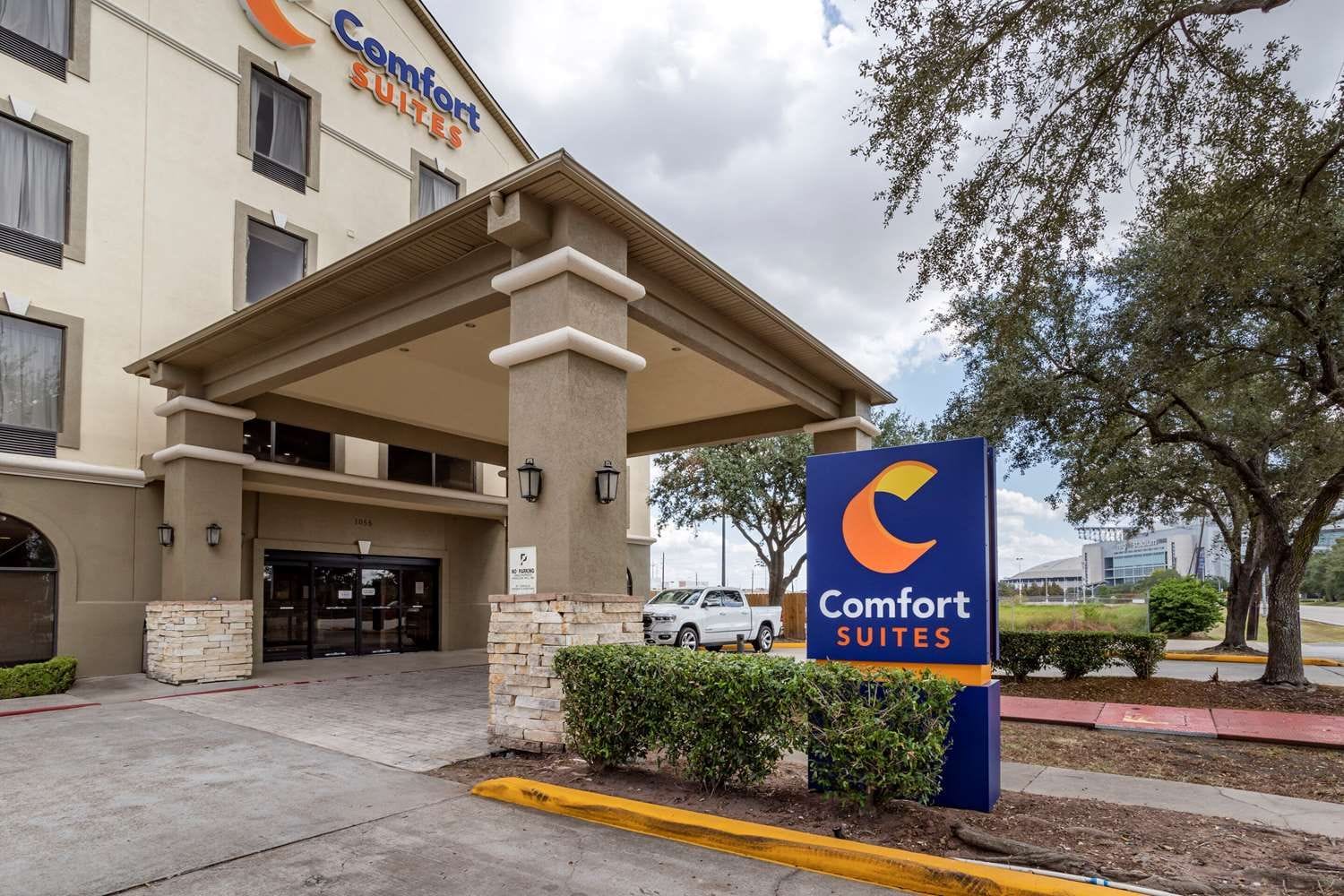 A Comfort Suites hotel entrance with a covered entrance, stone pillars, and a parking lot.