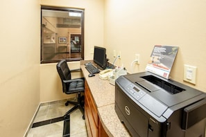 A small office with a desk, a computer, a printer, and a window.