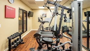 Un gimnasio con equipo de ejercicio, un reloj y un letrero motivacional.