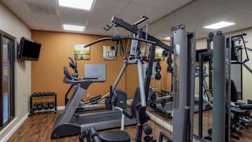 A gym with cardio machines, weightlifting equipment, and a television on the wall.