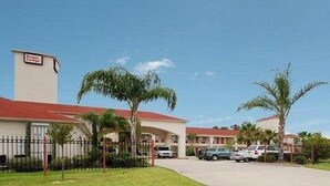 A hotel with a red roof, a signboard, and a parking area with cars. - Red Roof Inn & Suites Houston Humble/iah Airport (Humble)