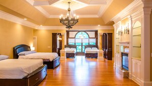 A spacious bedroom with two large beds, a chandelier, a fireplace, and a large window with a view. - Large House w/ Private pool - perfect for Golfing Groups 12 beds in 6 bedrooms (Pinehurst)