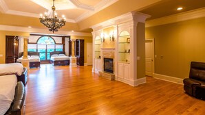A spacious bedroom with a large window, a fireplace, and a chandelier. - Large House w/ Private pool - perfect for Golfing Groups 12 beds in 6 bedrooms (Pinehurst)