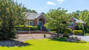 A two-story brick house with a front entrance, a covered porch, and a well-maintained lawn. - Large House w/ Private pool - perfect for Golfing Groups 12 beds in 6 bedrooms (Pinehurst)
