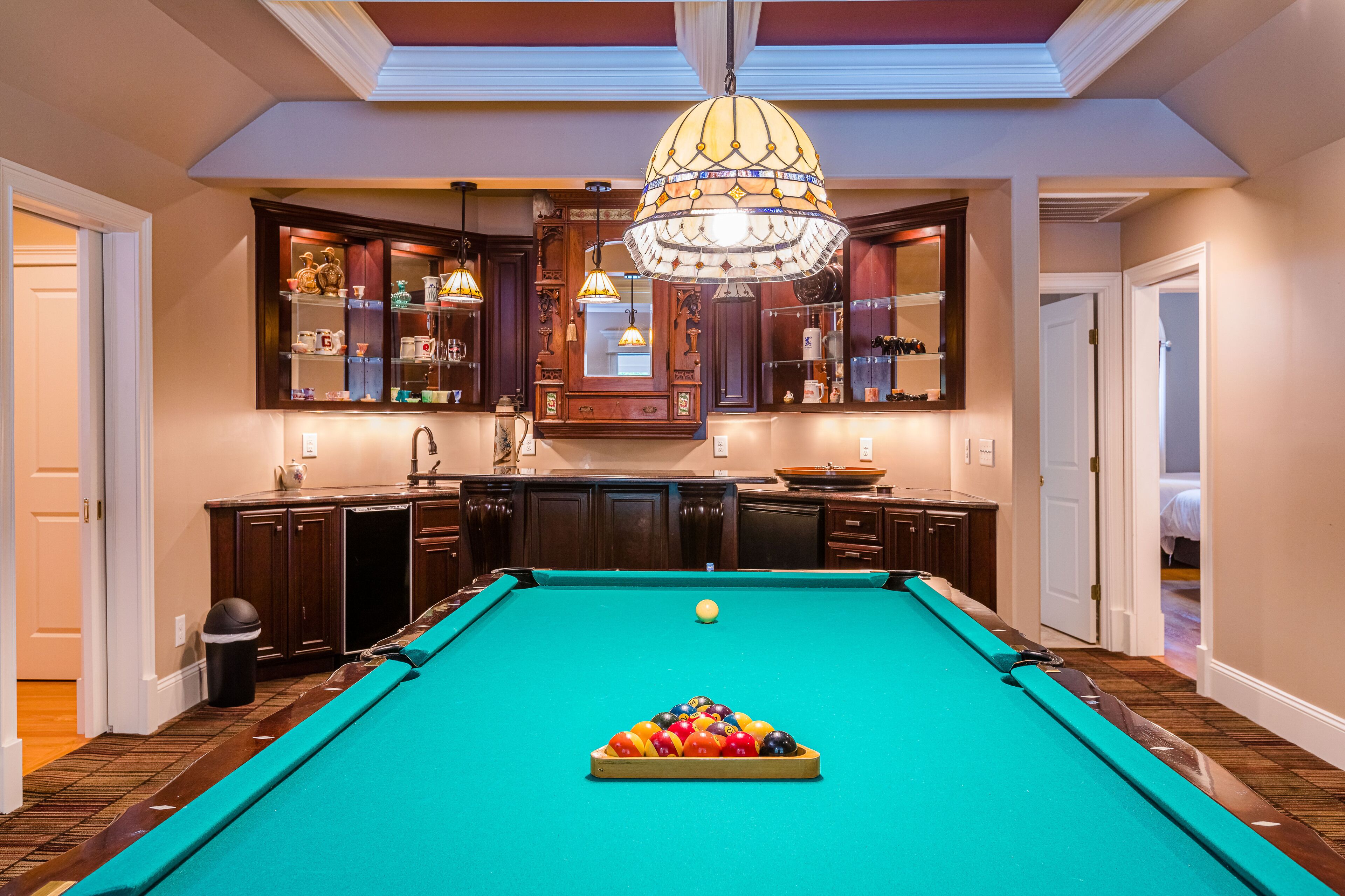 Une table de billard dans une pièce dotée de meubles en bois et d’un lustre.
