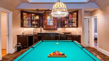 Une table de billard dans une pièce dotée de meubles en bois et d’un lustre.