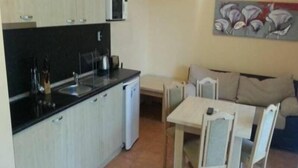A compact kitchen with a dining area, a microwave, and a painting on the wall. - Marack2 (Nessebar)