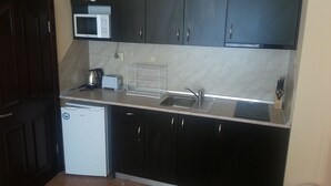 A compact kitchen with dark cabinets, a microwave, a toaster, and a sink. - Marack2 (Nessebar)