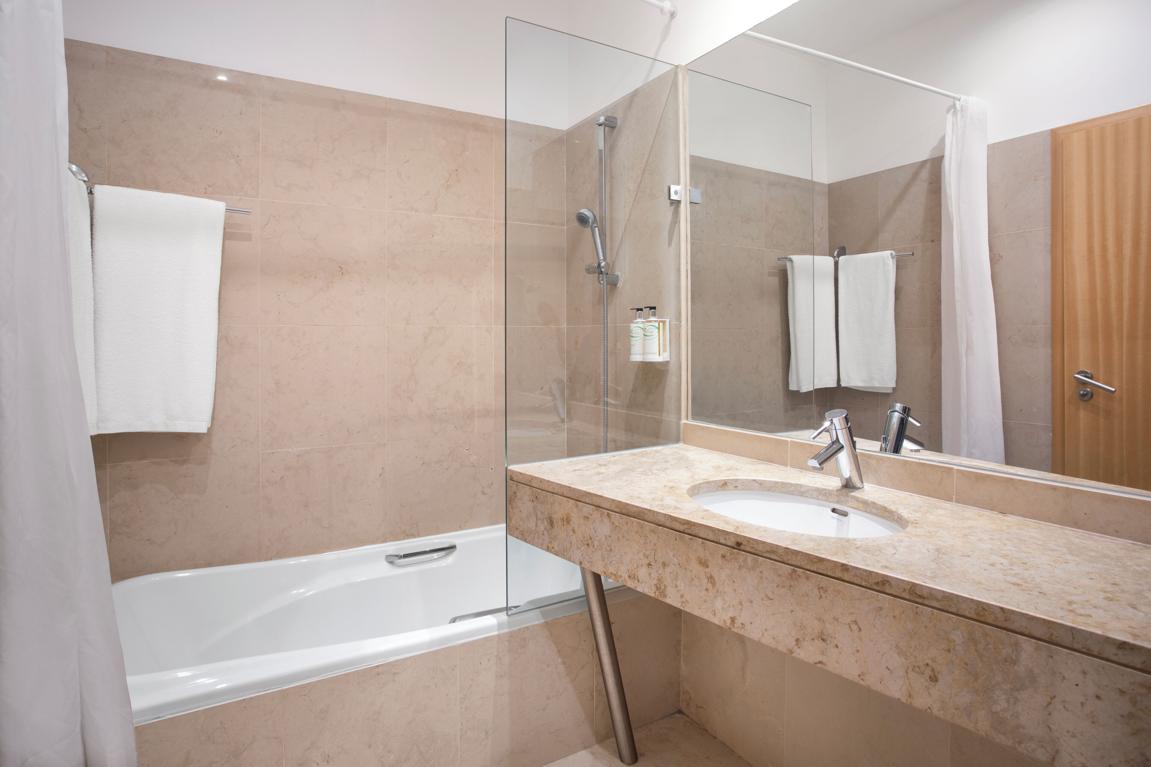 A modern bathroom with a glass-enclosed shower, a bathtub, and a marble countertop sink.
