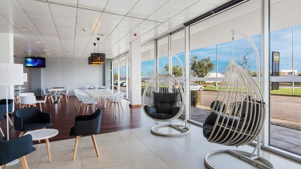 Een modern interieur met een zithoek, inclusief een hangstoel, witte tafels en stoelen.