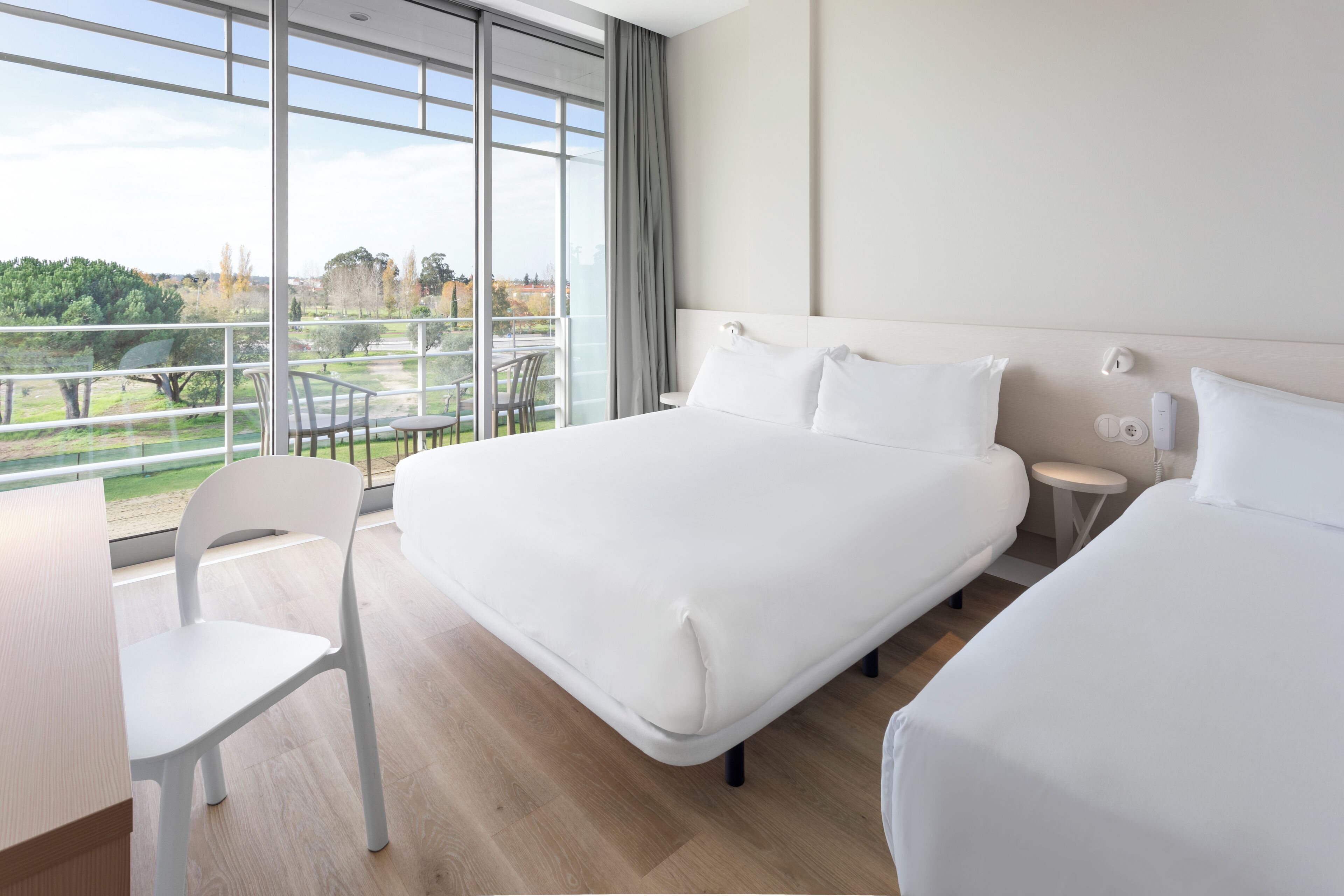 Une chambre d’hôtel avec un grand lit, un bureau et une chaise. Elle dispose d’un balcon avec vue sur la ville.