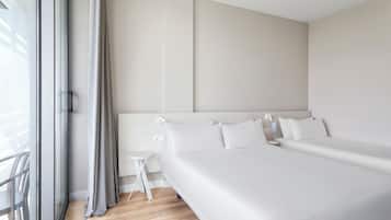 Camera d'albergo moderna con un letto grande, un comodino e vista sull'esterno tramite una porta scorrevole in vetro.