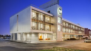 Een modern hotel met een grote glazen gevel, terras en een opvallend bord.