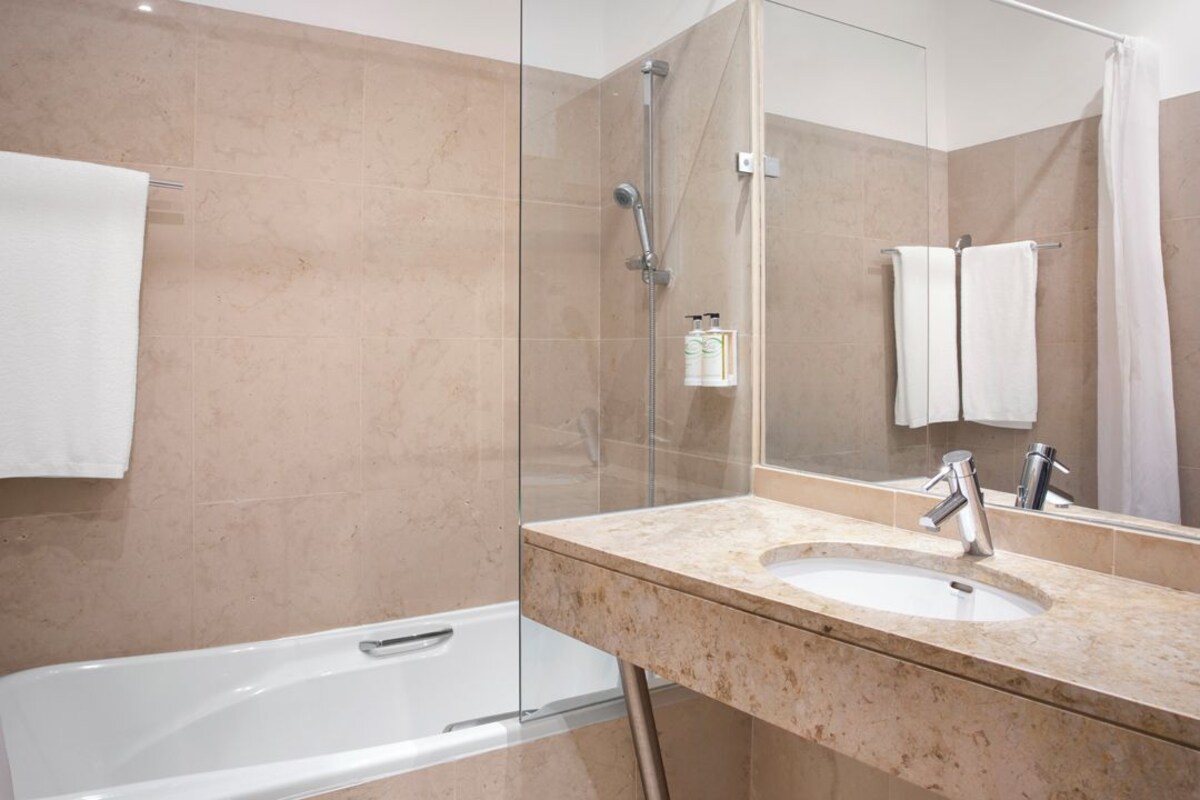 Une salle de bain avec une baignoire, un lavabo, une douche et un grand miroir.