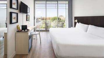 Una camera d'albergo moderna con un letto grande, una scrivania con una sedia, un tavolino e un balcone con sedie.