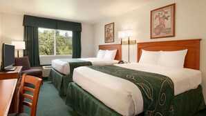 A hotel room with two beds, a desk with a chair, a TV, and a window with curtains. - Travelodge by Wyndham Dunsmuir (Dunsmuir)