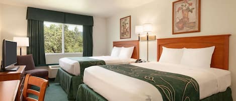 Habitación de hotel con dos camas, un escritorio con silla, un televisor y una ventana con cortinas.