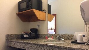 A kitchen with a granite countertop, a coffee maker, a microwave, and a sink. - Travelodge by Wyndham Dunsmuir (Dunsmuir)