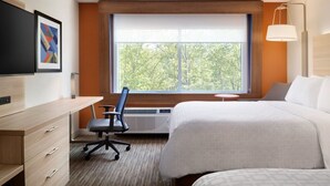 A hotel room with a bed, desk, chair, and a large window with a view of trees. - Holiday Inn Express Canton Potsdam (Canton)