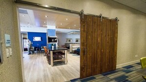 An interior space with a wooden sliding door, a reception area with a blue wall, and a seating area with a table and chairs. - Holiday Inn Express Canton Potsdam (Canton)