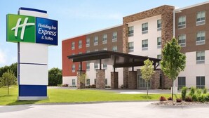 A Holiday Inn Express & Suites building with a modern design, featuring a covered entrance and a landscaped area with trees and shrubs. - Holiday Inn Express Canton Potsdam (Canton)