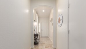 A hallway with a white door at the end, a small table with a lamp, and a wall-mounted sign. - Ahwatukee/Foothills-Golfer's Paradise! Desert Vacation Retreat/Gated Community! (Phoenix)