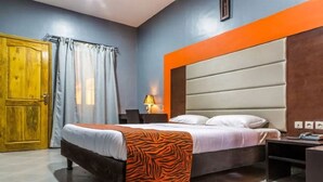 Un dormitorio con cama, una puerta de madera, una mesita de noche y una lámpara.