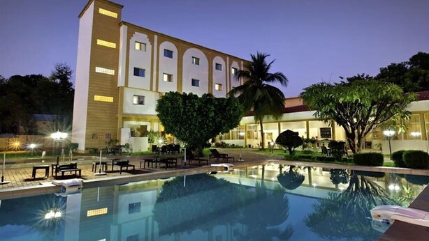 Un hotel con piscina, mobiliario exterior y una fachada bien iluminada.