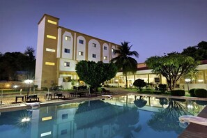 A hotel with a swimming pool, outdoor seating, and a well-lit facade. - Hotel Dunia Bamako (Bamako)