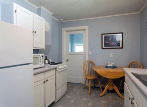 Compact kitchen area with a dining table and chairs, microwave, and stove.
