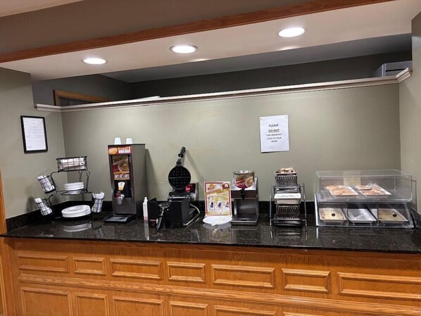 A breakfast counter with a waffle maker, coffee machine, and a sign instructing not to take breakfast food to your room. - Fairbridge Inn Suites Fort Wayne (Fort Wayne)